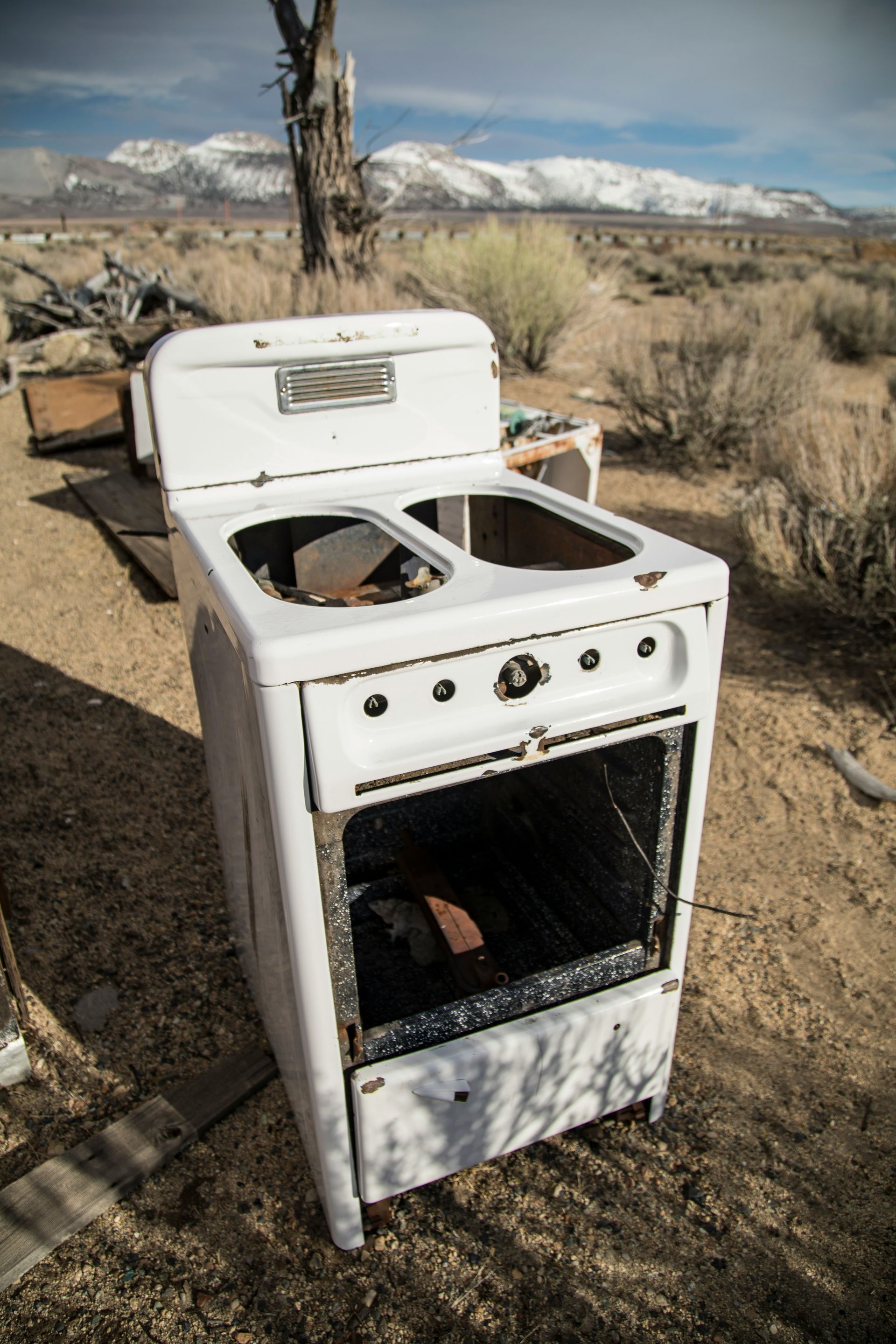 an old stove sitting in the middle of a dirt field